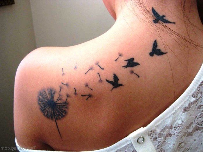 Kvinna med fågel tatuering på ryggen, blowball med flygande frön och fåglar
