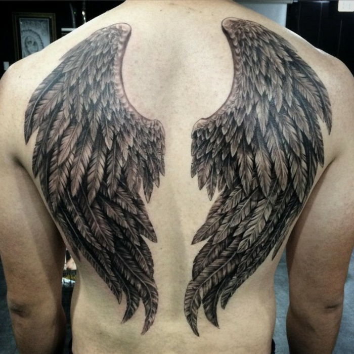muž a jeho anjelské tetovanie s dvoma čiernymi anjelskými krídlami s dlhým čiernym perom