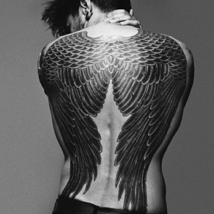 człowiek z wielkim, bajkowym, czarnym tatuażem anioła - oto dwa czarne skrzydła anioła z długimi czarnymi piórami