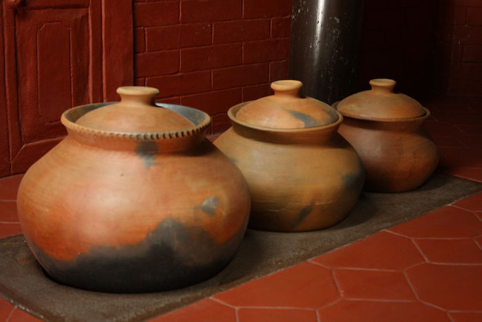 tre vasi di terracotta di colore marrone-nero, recipiente di cottura con coperchio, pavimento piastrellato, parete piastrellata