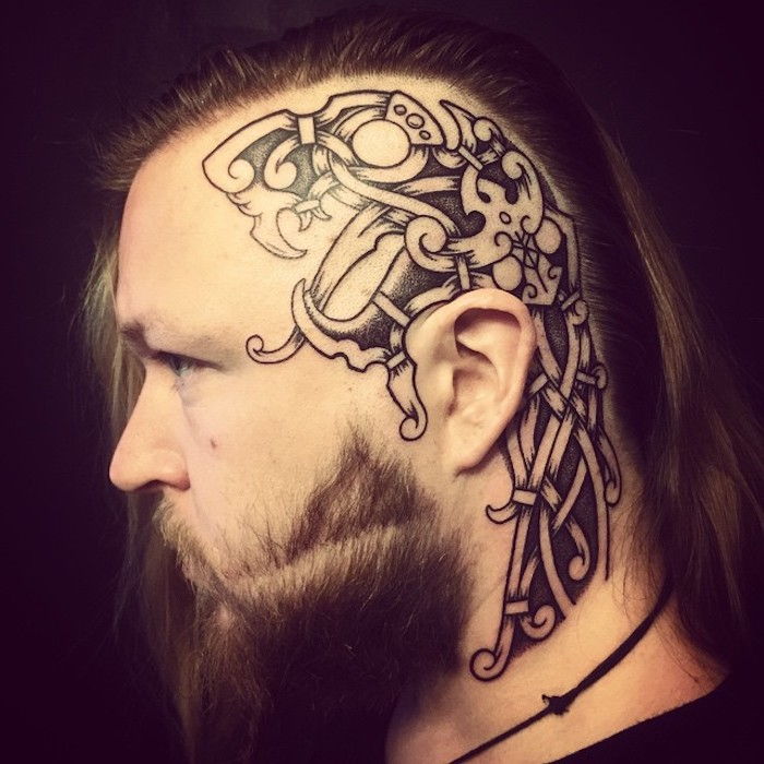 uomo con i capelli lunghi e la barba lunga, tatuando la sua testa