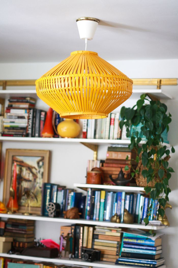 Lampada vintage, mensole con molti libri su di esso, pianta d'appartamento, foto, look retrò