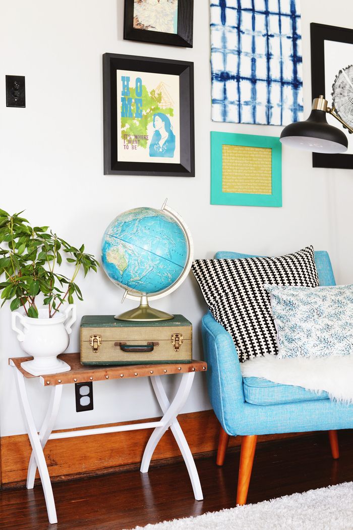 Mobili vintage per il soggiorno, poltrona blu con cuscino decorativo, pianta d'appartamento, globo e valigia