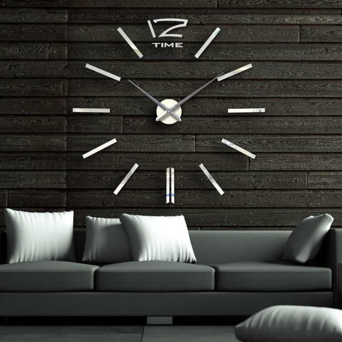 wall-clock-XXL-metal dial-drevená stena-obklady tmavo šedá-pohovka a biele vankúše