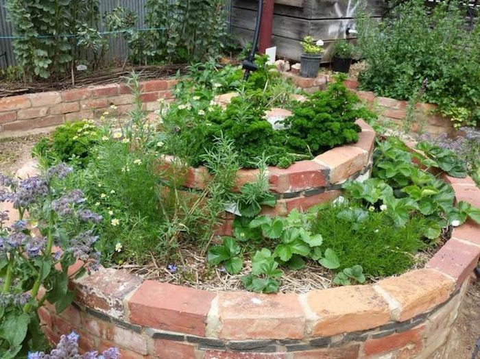 Vi anbefaler at du ser på denne urte spiral ideen med grønne planter og små urter og små steiner