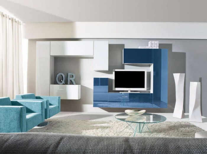 kast muur tv muur in blauw en wit glazen tafel in het midden van de kamer twee blauwe fauteuils
