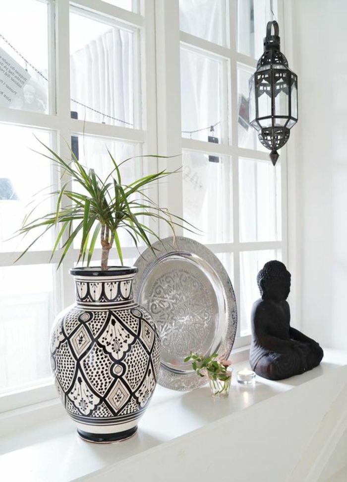Dekorácia okien so suvenírmi: dekoratívna keramická kvetinová váza, kovová doska, socha Buddhu z dreva