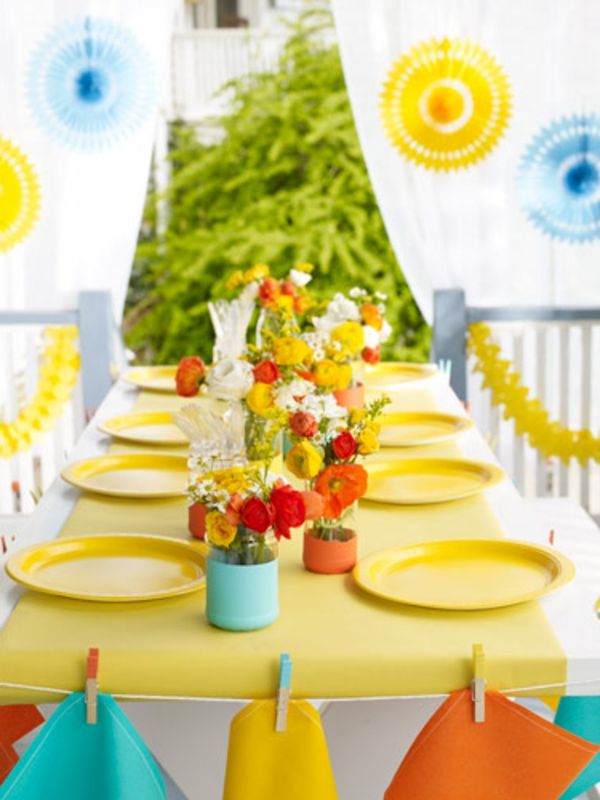 krásna letná stolová dekorácia s mnohými farebnými kvetmi a žltými tanieremi