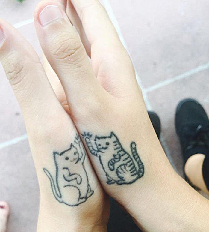 To są dwa małe czarne koty i dwie ręce - świetne pomysły na tatuaż