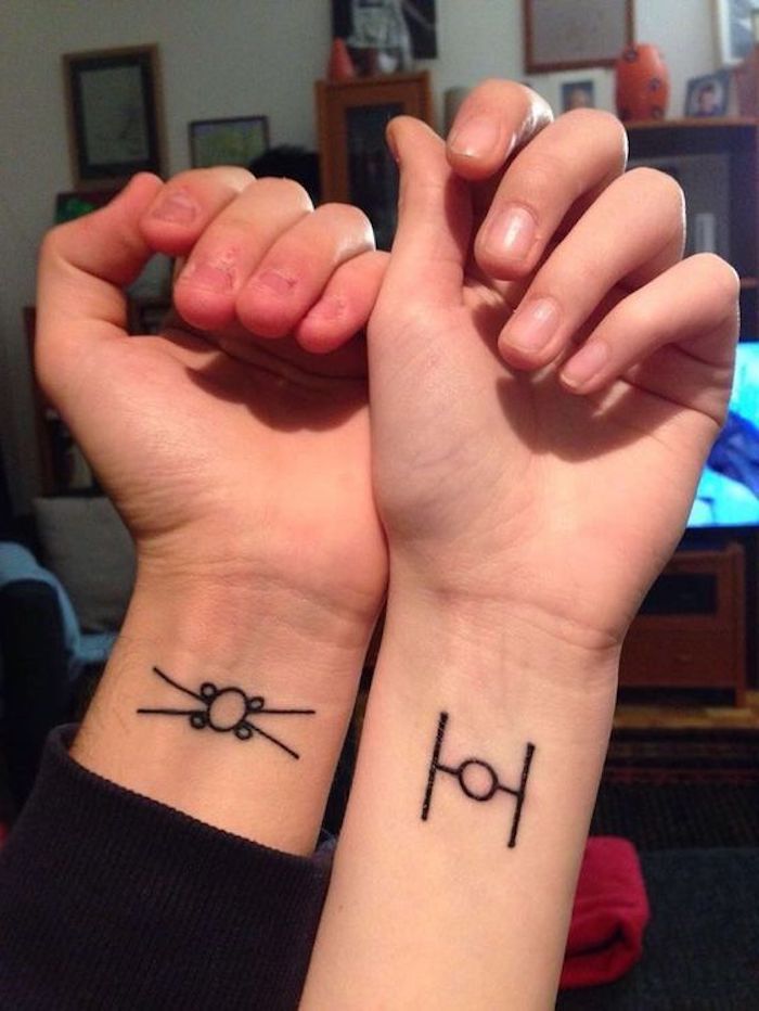 myšlienka na tetovanie pre pár na zápästí - dve ruky s malým čiernym tetovaním s lietajúcimi vesmírnymi loďami hviezdnych vojen
