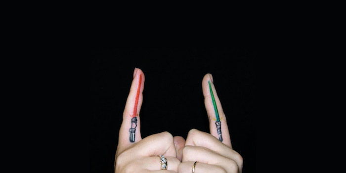 dve ruky a dva prsty s malým červeným svetelným mečom a tetovanie hviezdnych vojen s malým zeleným svetlom