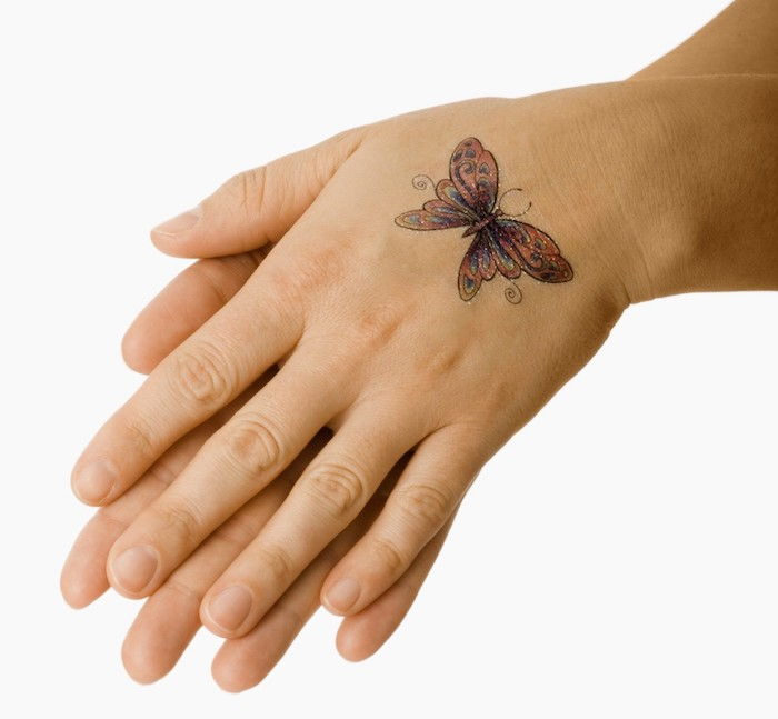 čia yra dvi rankos ir spalvinga maža skraidanti drugelis su spalvingais sparnais - idėja nuostabaus drugelio tatuiruotės