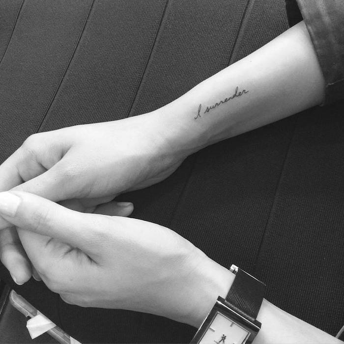 Un tatuaj negru mic pe încheietura mâinii - un ceas și un tatuaj negru mic pe tatuaj. idee pe tema scrisului de tatuaj