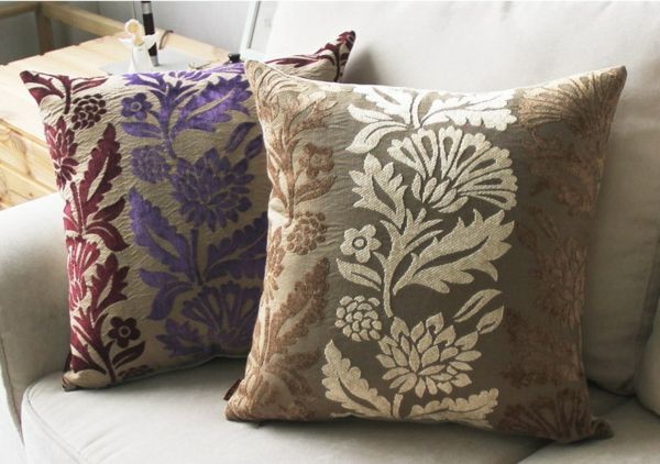 dvi gražios sofos pagalvėlės violetinėse ir beige kūrybingose ​​ornamentuose
